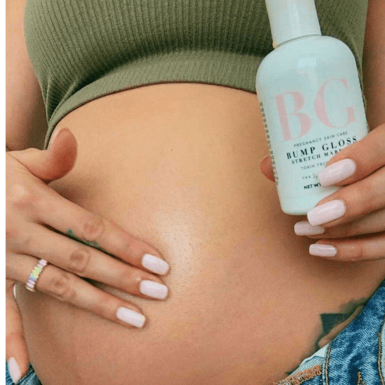 Pregnant mom holding a bottle of 'Bump Gloss' against their stomach.