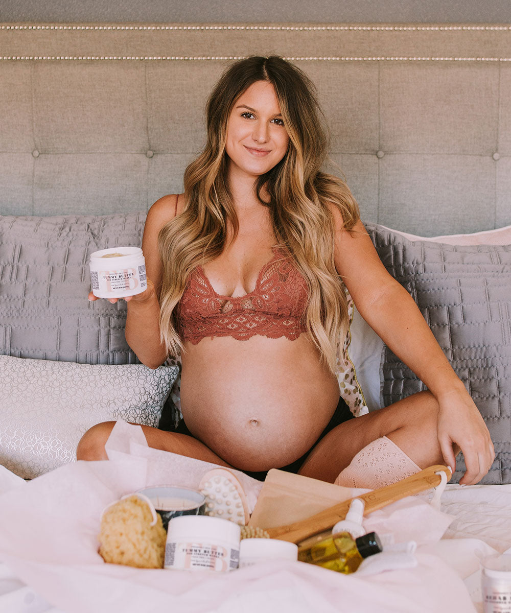 Pregnant woman relaxing with The Spoiled Mama pregnancy skincare products, including Tummy Butter, Bump Gloss, and Body Polish as part of a self-care routine.