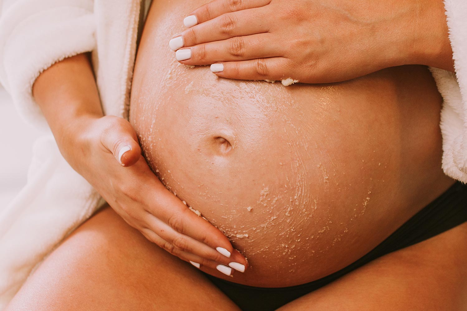 Pregnant belly with moisturizer applied illustrating trimester-specific pregnancy skincare recommendations.