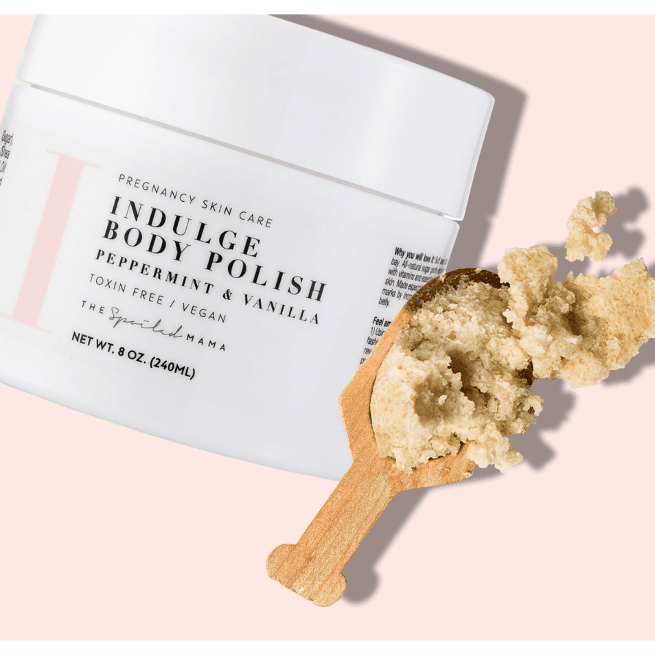 Indulge Body Polish pregnancy skin care product with a wooden applicator on a pink background