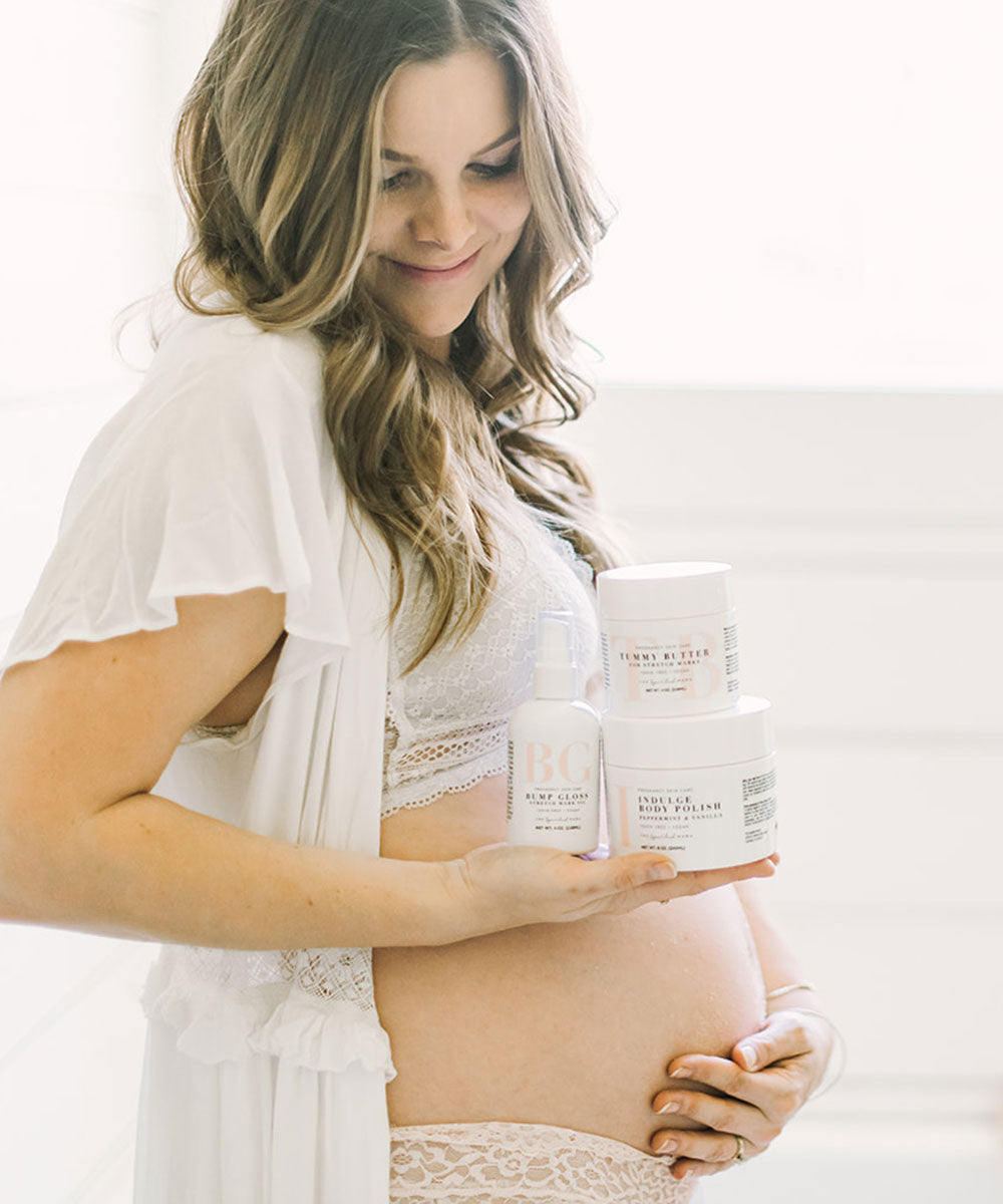 Pregnant woman holding The Spoiled Mama Tummy Butter, Bump Gloss, and Body Polish as a complete pregnancy skincare routine for healthy-looking, hydrated skin.