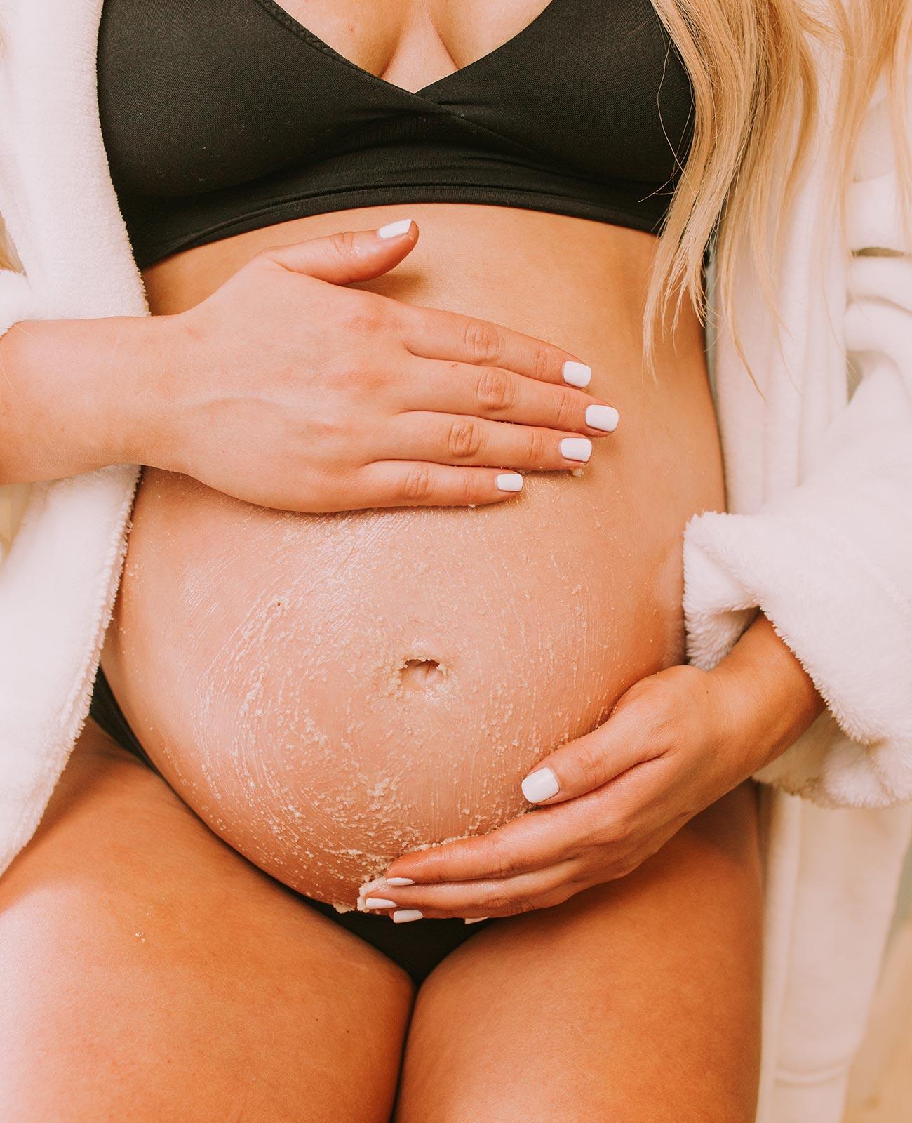 Close-up of pregnant woman holding belly, showcasing OBGYN-recommended non-toxic skincare for pregnancy and postpartum. 