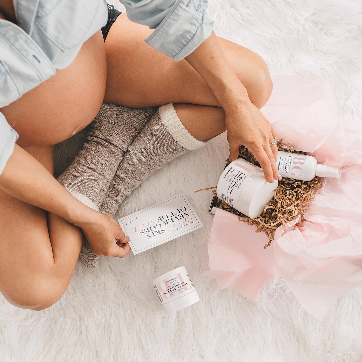 Pregnant woman opening The Spoiled Mama pregnancy skincare gift set featuring Tummy Butter, Bump Gloss and self-care bundle.